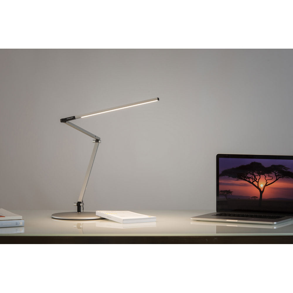 z-bar slim led desk lamp by koncept lighting on a white desk lighting a laptop