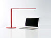 Matte red Lady 7 LED desk lamp on table over laptop