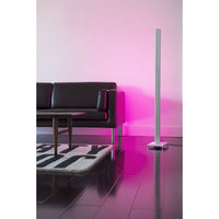 Tono LED floor lamp next to a black sofa washing the wall in pink light