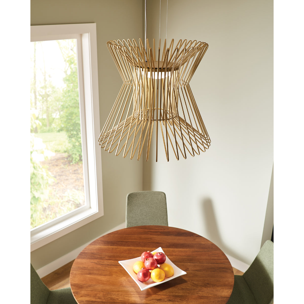 syrma grande pendant in satin gold hanging over round wood dining table